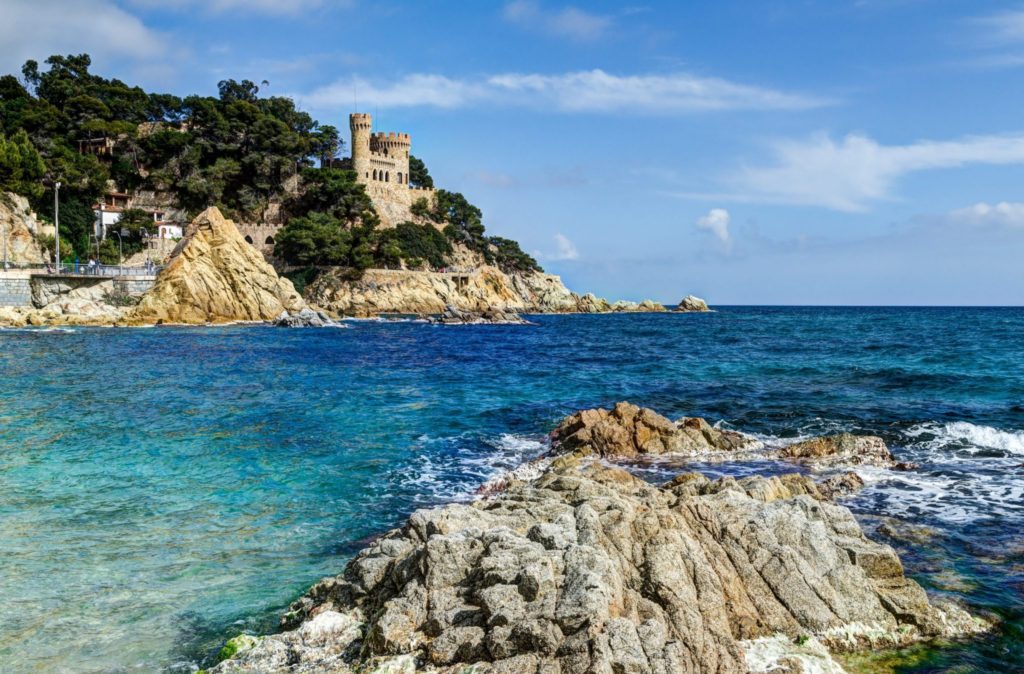 A view of the ocean and a castle on top of a hill.