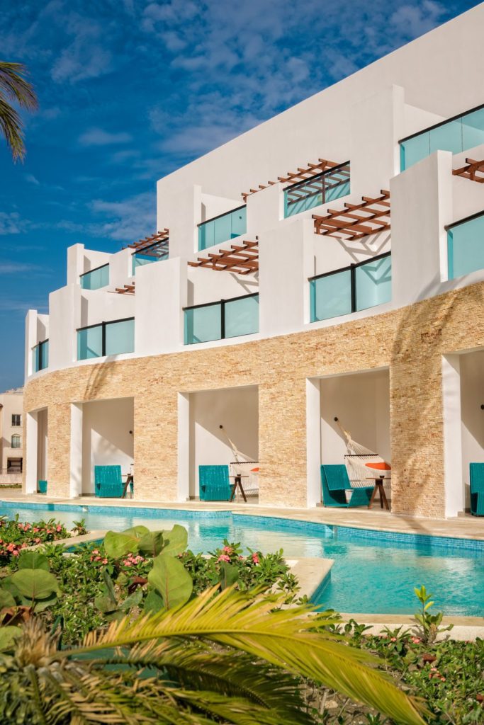 A pool and some chairs in front of a building.