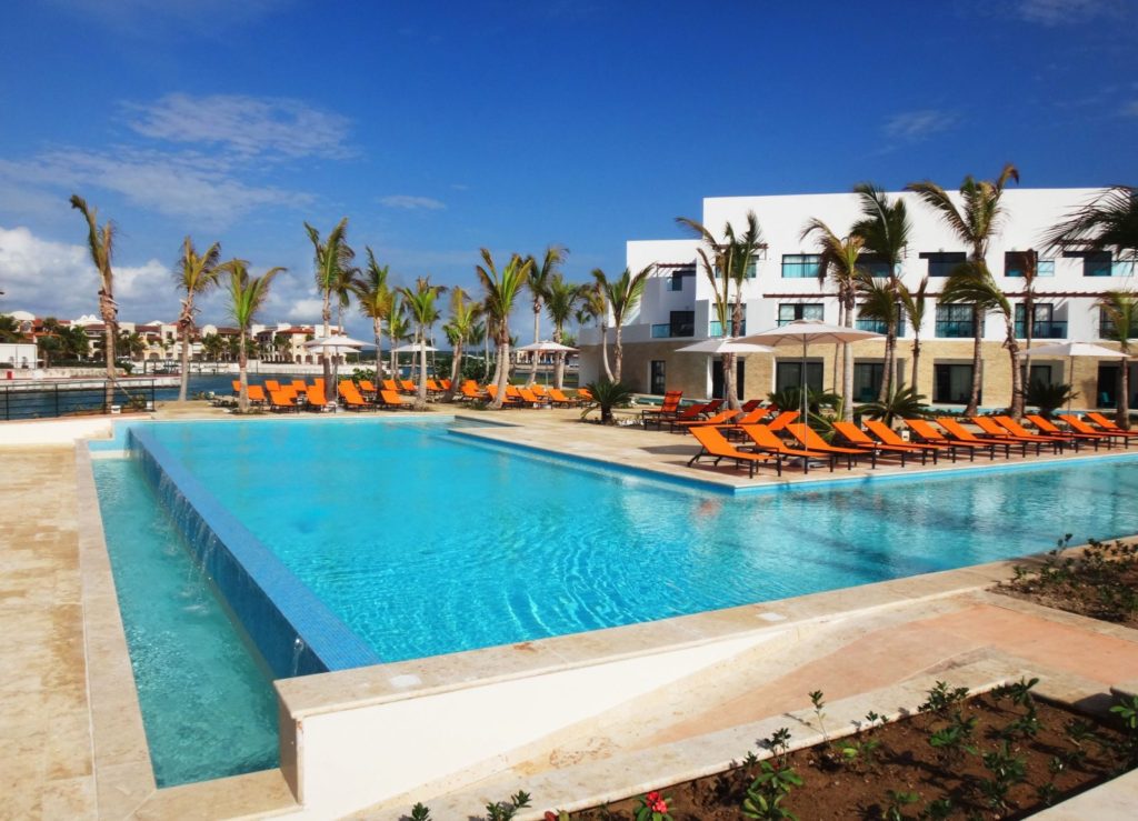 A large swimming pool with orange lounge chairs.