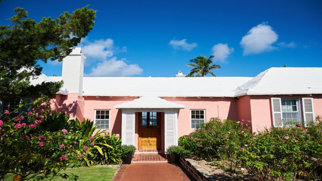 A pink house with a white roof and door.