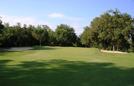A golf course with trees and grass on the side.