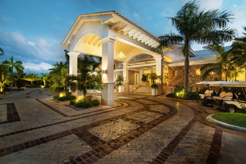 A large white building with a walkway and palm trees.