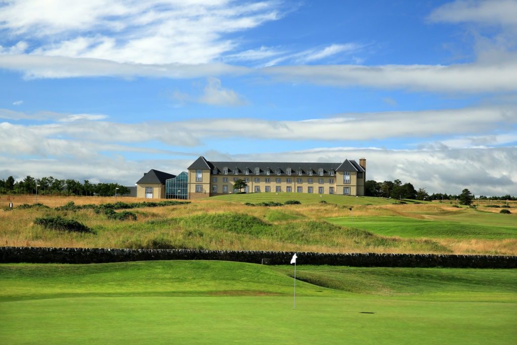 A large building on top of a green golf course.