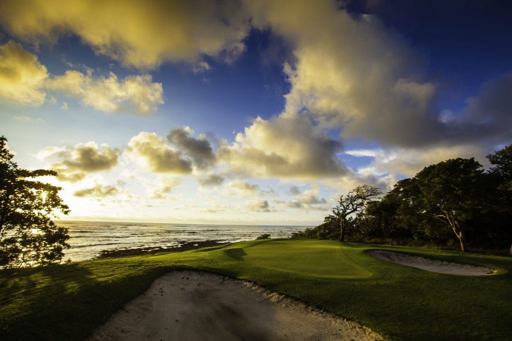 A golf course with the ocean in the background.