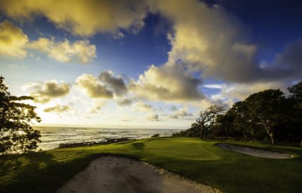 A golf course with the ocean in the background.