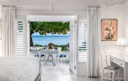 A bedroom with a view of the ocean and a dining table.