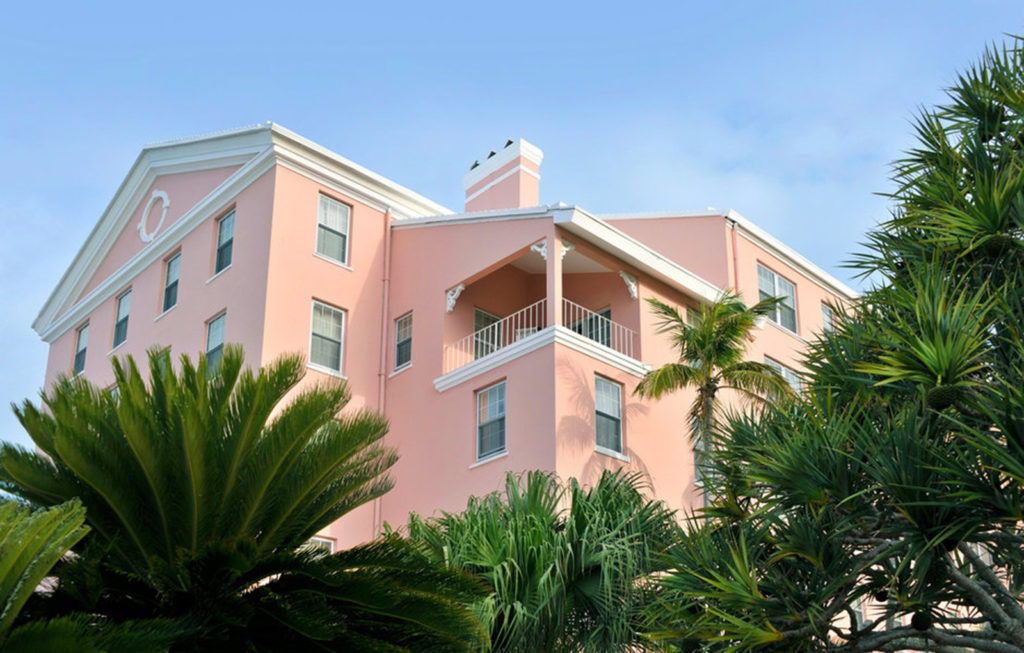 A pink building with palm trees in front of it.