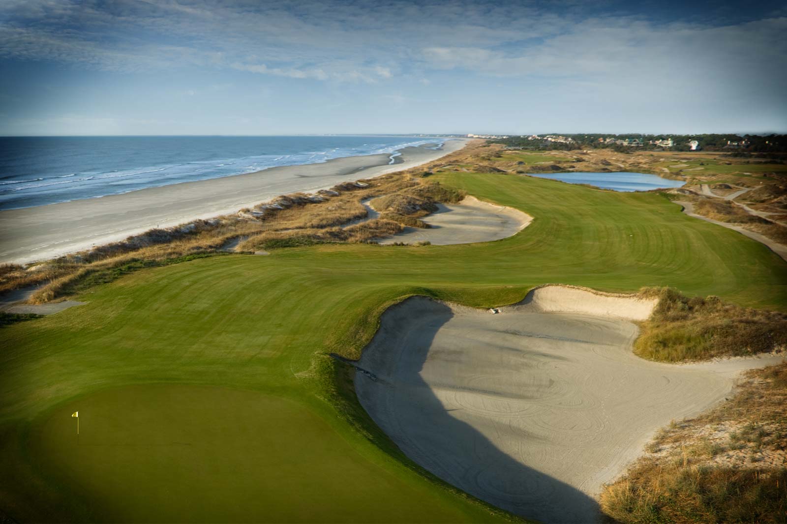 A golf course with sand and water on the side of it.