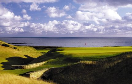 A golf course with an ocean view and grass.