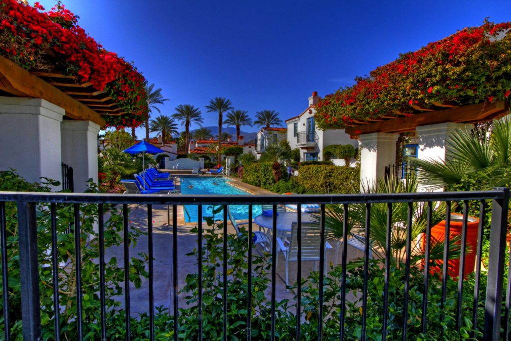 A view of a pool and some trees from the balcony.