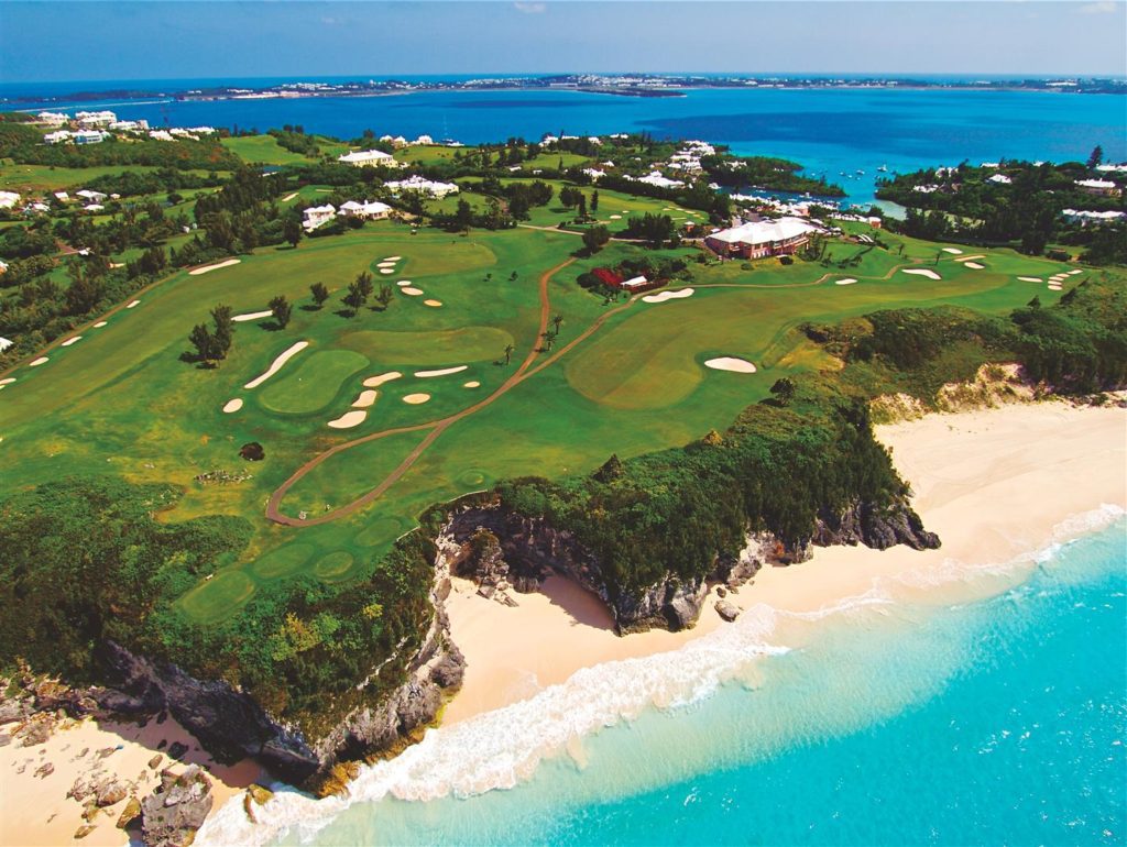 A golf course with a sandy beach and ocean.