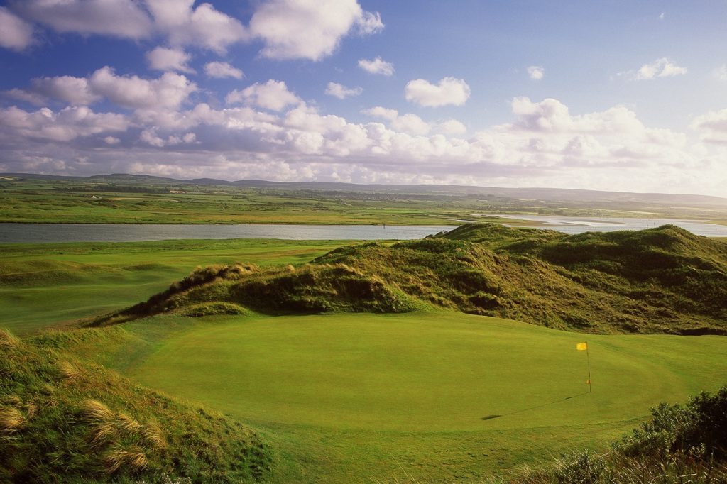 A golf course with green grass and water.