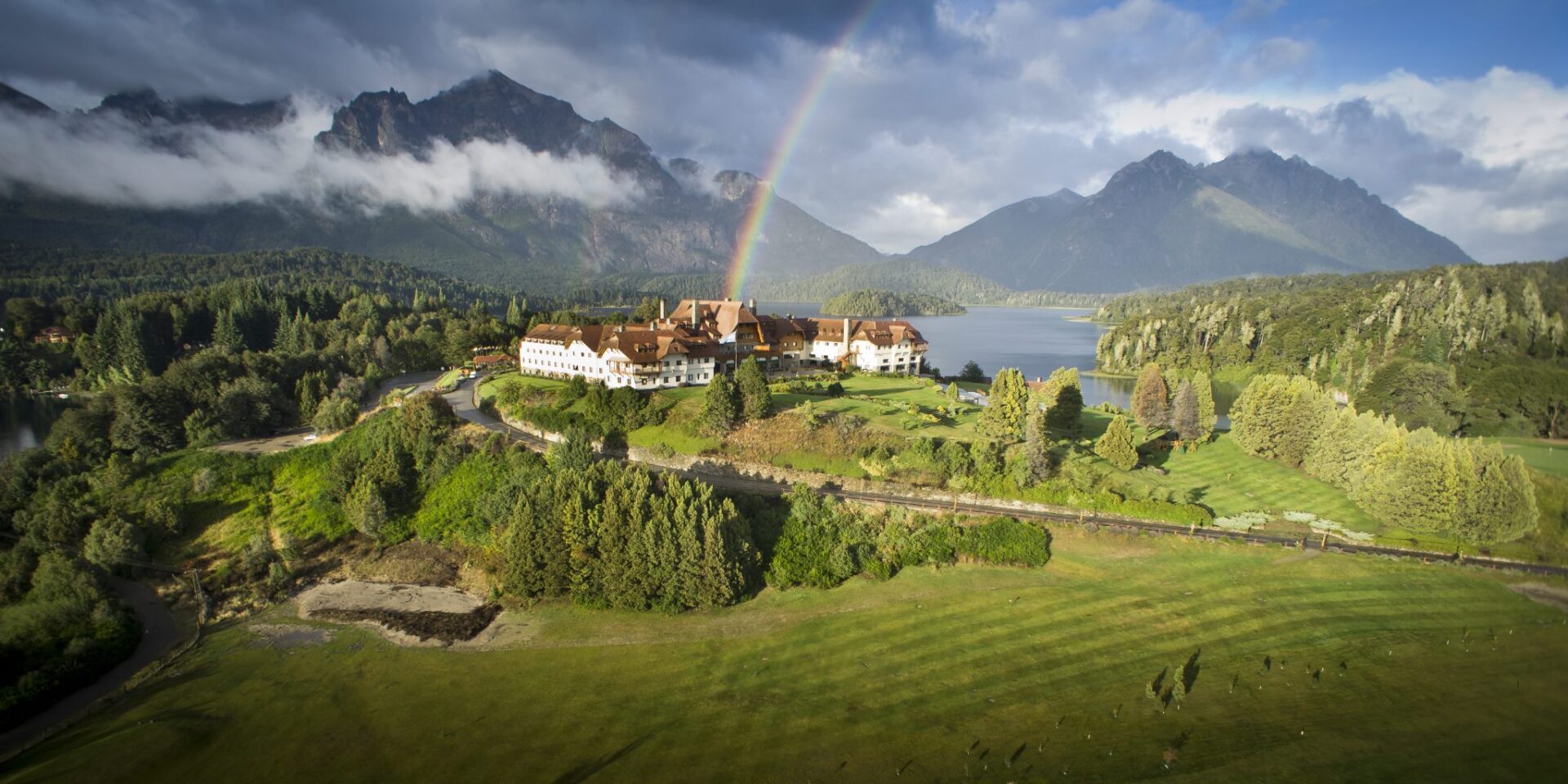 A rainbow over a large lake and a resort.