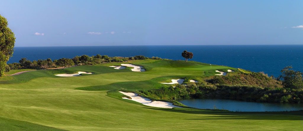 A golf course with water and trees in the background.