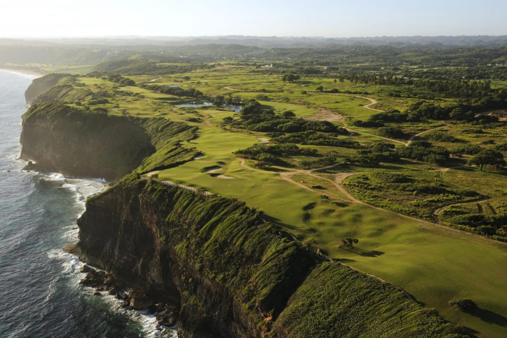 A view of the ocean from above shows a golf course.