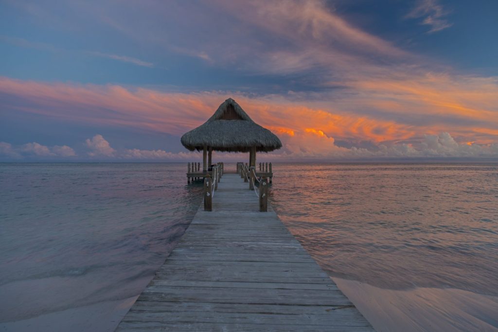 A pier with an umbrella over it at sunset.