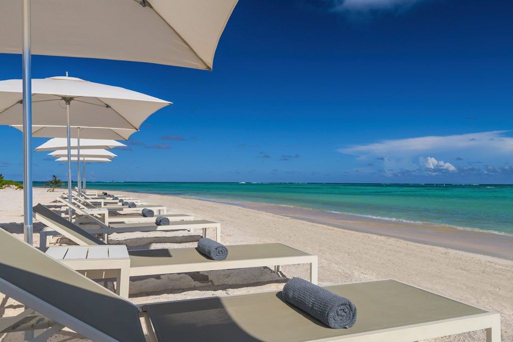 A beach with many chairs and umbrellas on it