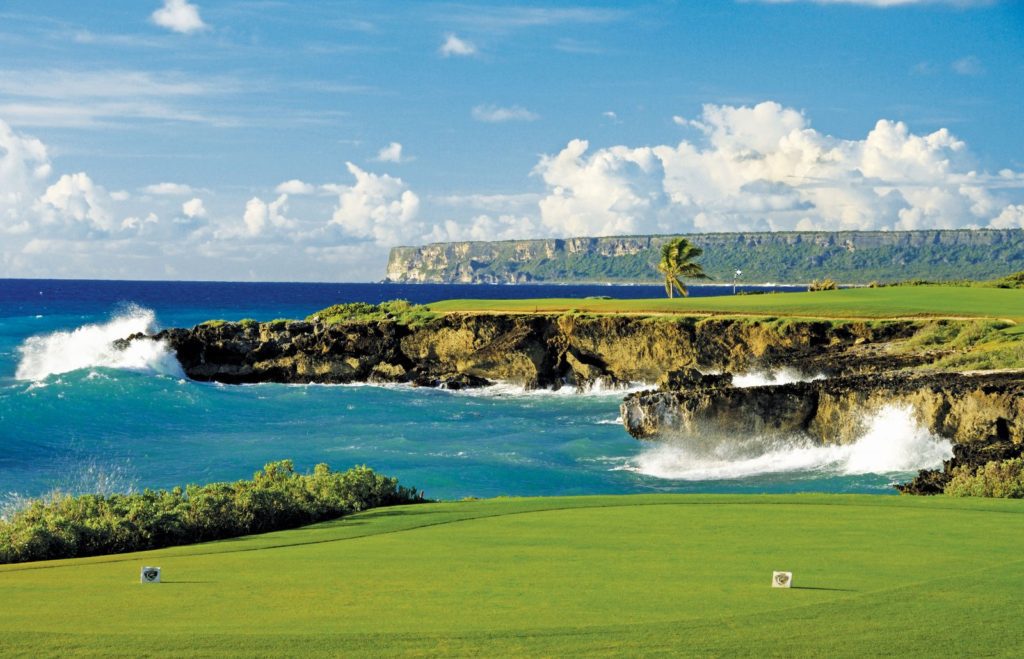 A golf course with water and rocks in the background.