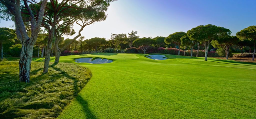 A golf course with many green areas and trees.