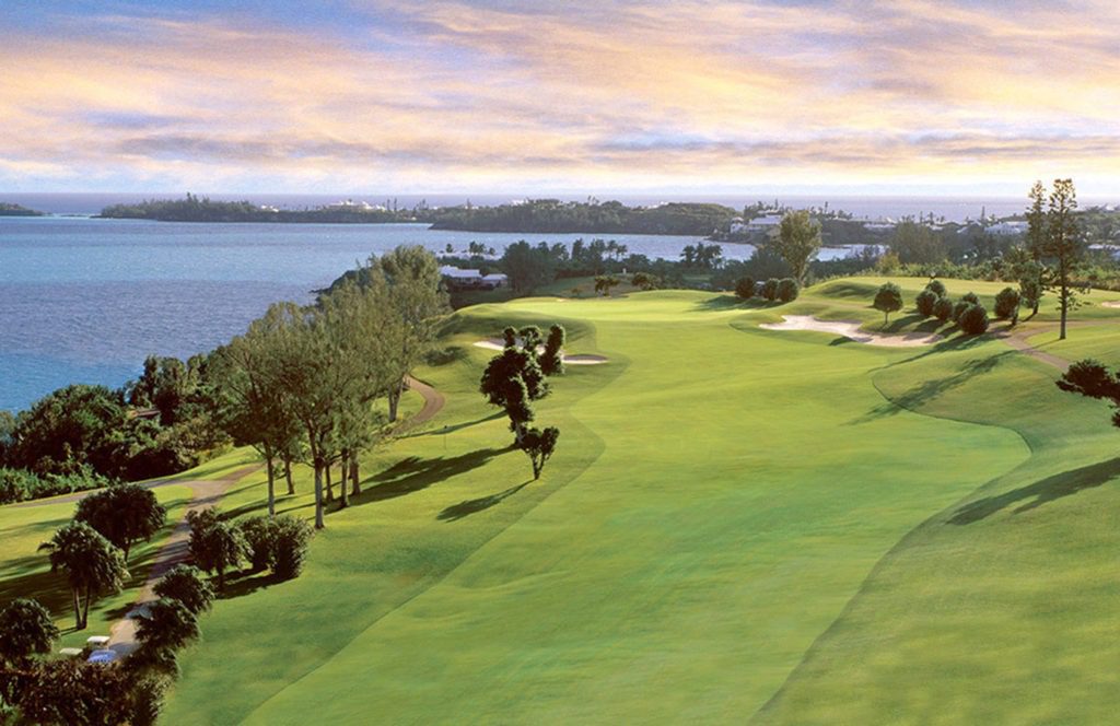 A painting of a golf course with trees and water in the background.