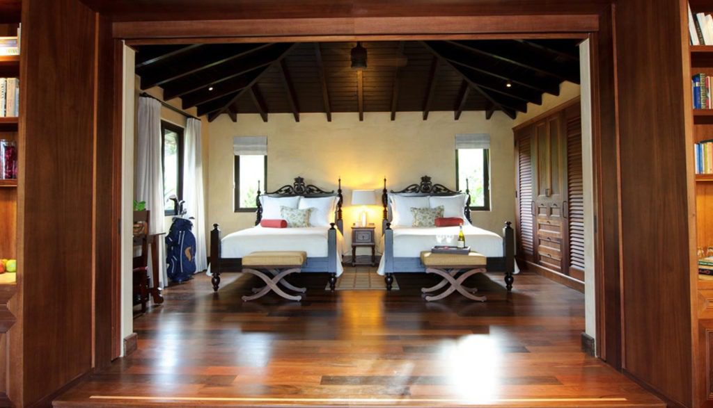 Two beds in a room with wooden floors and walls.