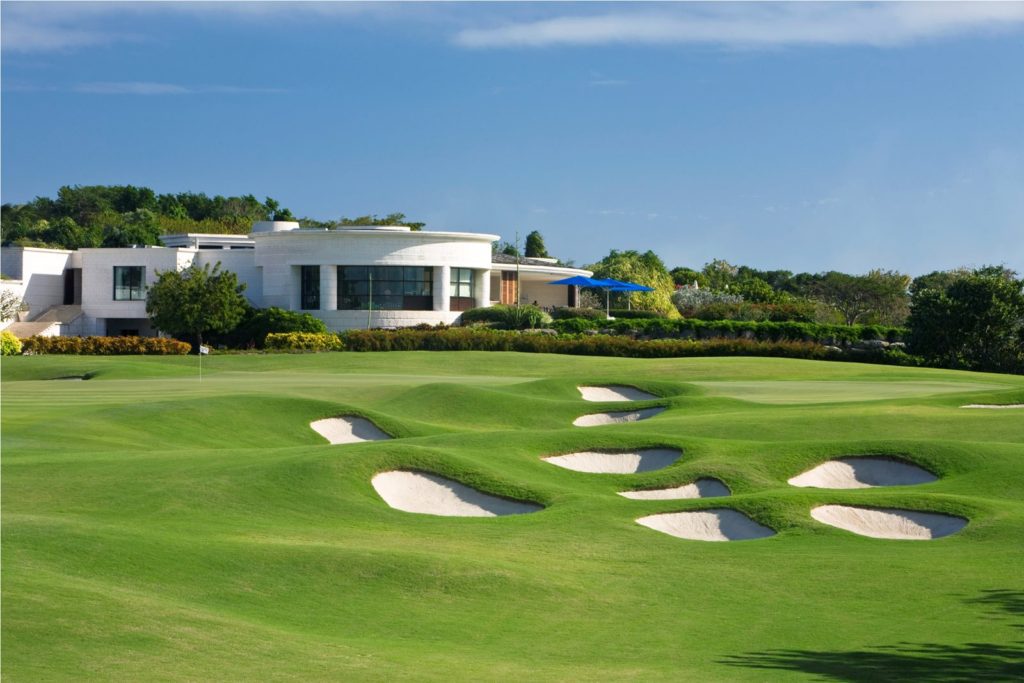 A golf course with many green areas and white buildings.