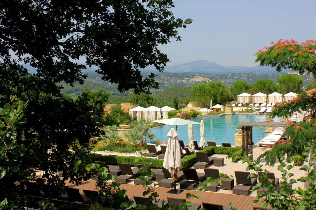 A pool with an umbrella and chairs in the foreground.