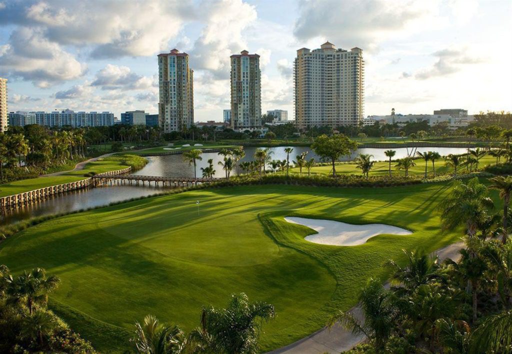 A golf course with many buildings in the background.