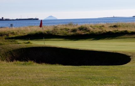 A golf course with a red flag and green on the side.