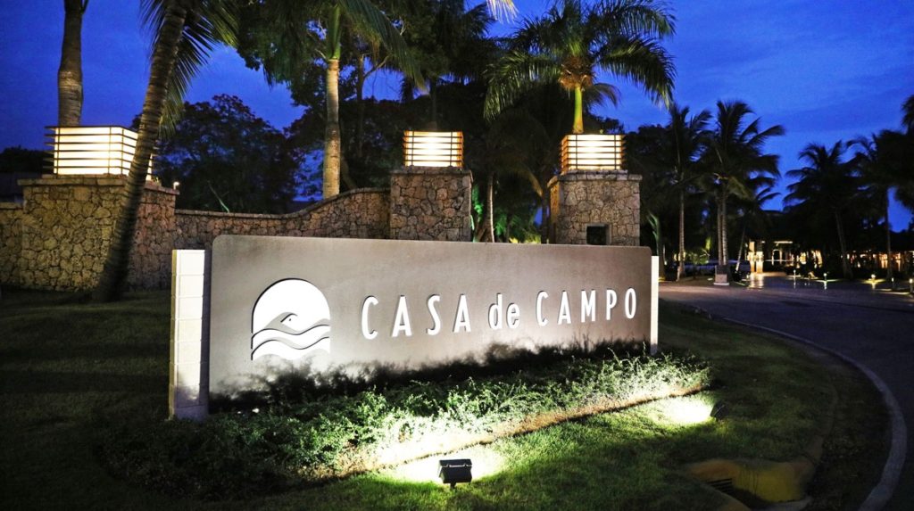 A sign that says casa de campo lit up at night.