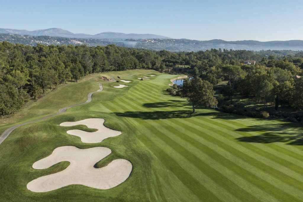 A golf course with many green areas and trees.