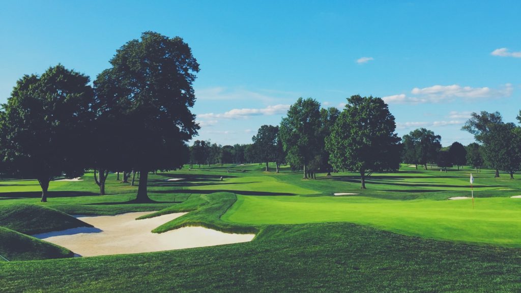 A golf course with trees and green grass.