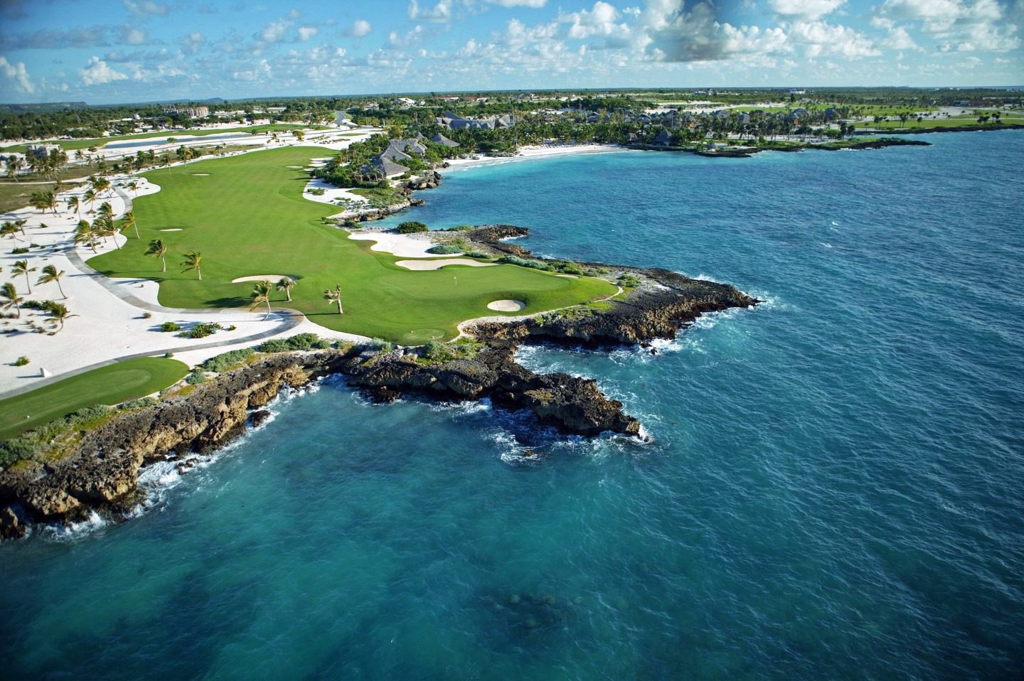 A view of the ocean from above shows a golf course.