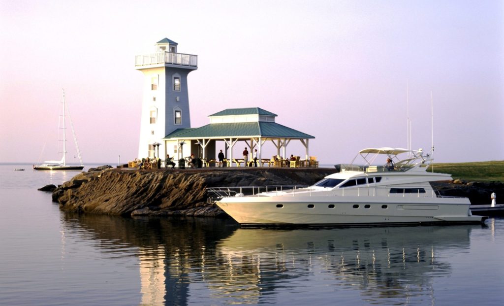 A boat is parked in front of a lighthouse.