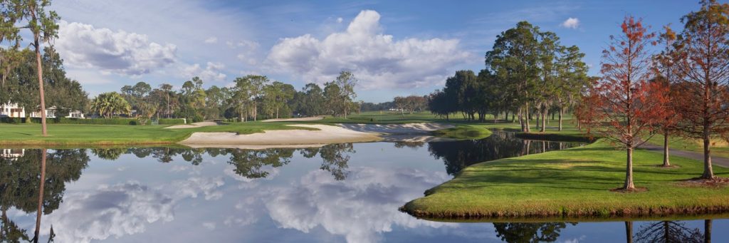 A golf course with water and trees in the background.