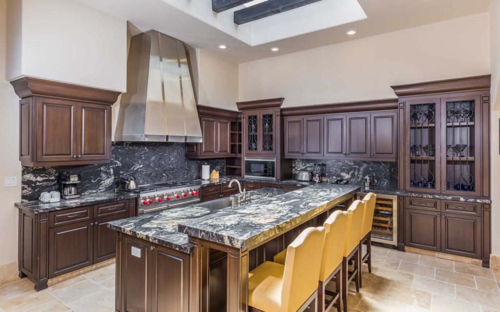 A kitchen with marble counter tops and wooden cabinets.