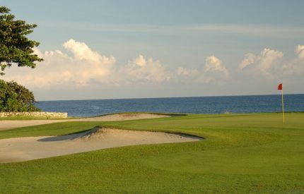 A view of the ocean from behind a golf course.