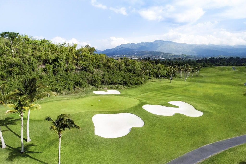 A golf course with trees and mountains in the background.