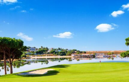 Golf course with water and blue sky.