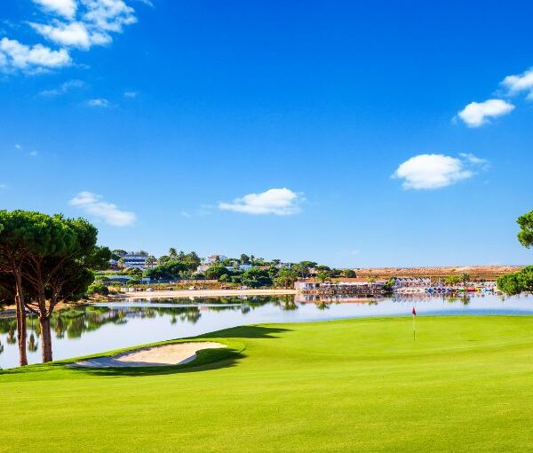 Golf course with water and blue sky.